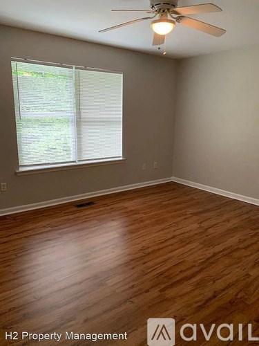 A room with wooden flooring and a ceiling fan.