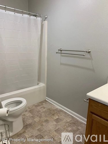 A white toilet in a bathroom with a white shower curtain.