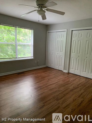 A room with a ceiling fan and wooden flooring.