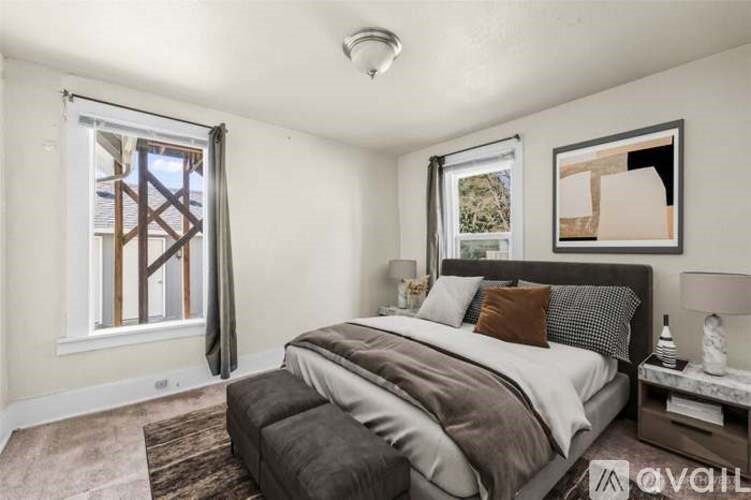 A bedroom with a large bed and a window with a view of a wooden structure.