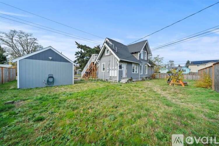 A house with a garage is situated on a grassy hill.