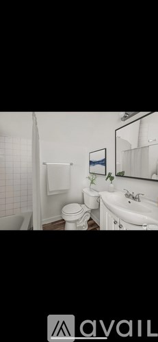 A small grey building with a white door and a green hose on the wall.