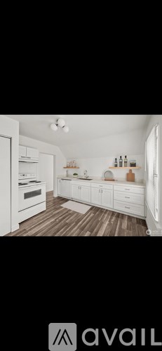 A modern kitchen with white cabinets and a wooden floor.