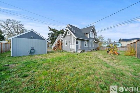 A house with a garage is situated on a grassy hill.