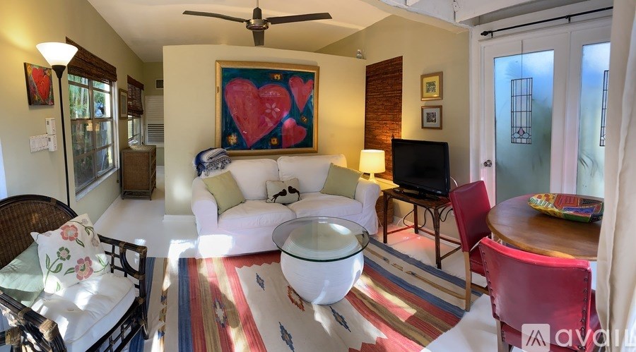 A living room with a white couch and a red heart painting on the wall.