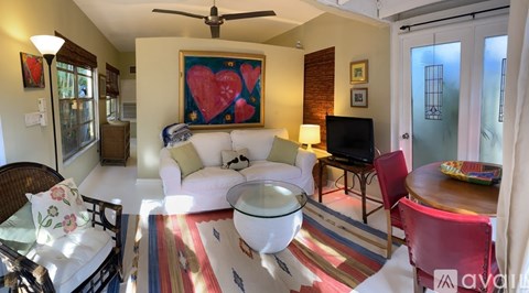 A living room with a white couch and a red heart painting on the wall.