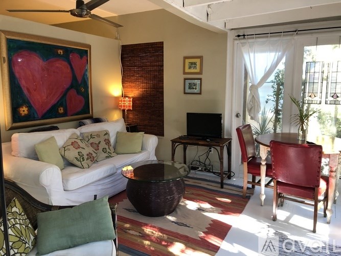 A living room with a white couch, a red chair, and a painting of two hearts.