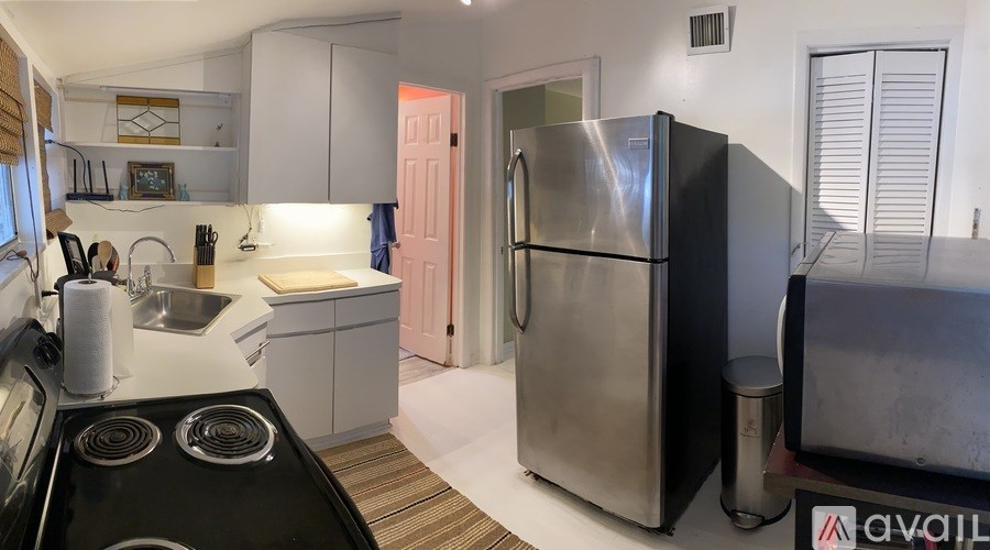 A kitchen with a black stove top oven and a large stainless steel refrigerator.