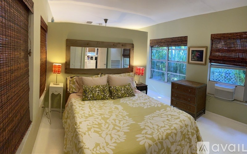 A bedroom with a bed, dresser, and window with blinds.