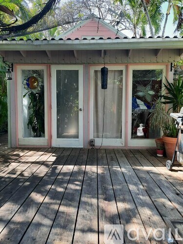 A wooden deck with a glass door and a plant on the right.