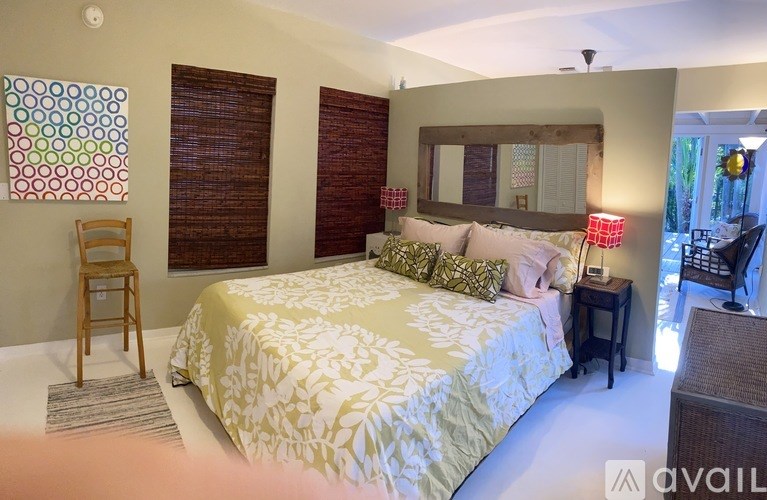 A bedroom with a bed, a chair, and a mirror.