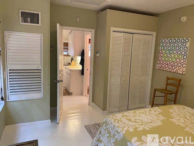 A room with a bed, a chair, and a wall hanging with circles.