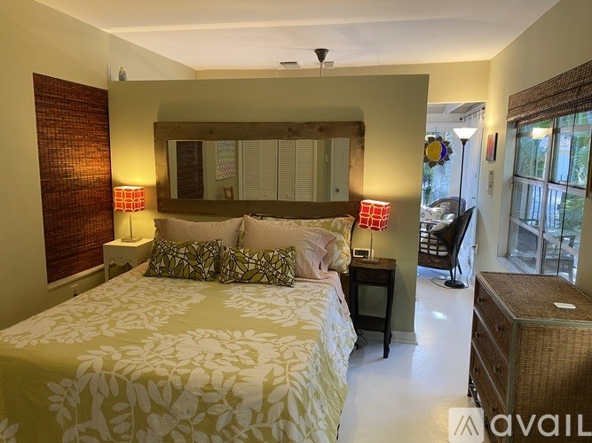 A bedroom with a bed, nightstand, and a window with blinds.