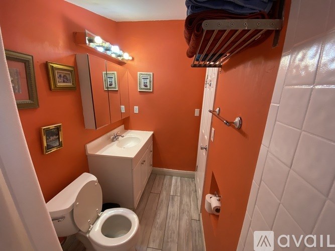 A bathroom with orange walls has a white toilet and sink.