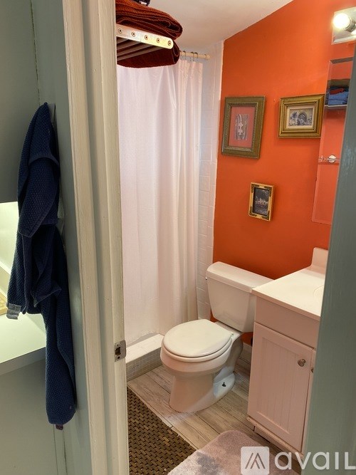 A bathroom with orange walls and a white toilet.