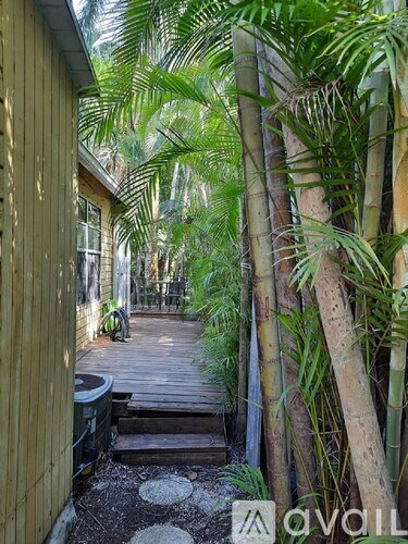 A wooden deck with a trash can and surrounded by trees.
