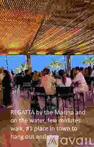 A group of people are sitting under a canopy by the water.