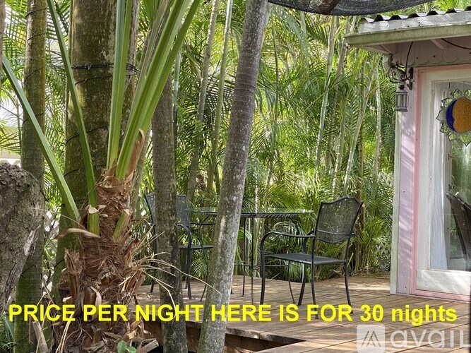A tropical setting with a chair and a sign offering a 30 night stay.
