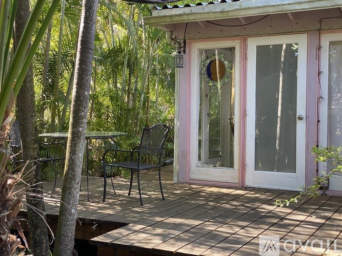 A patio with a chair and a table is surrounded by trees.