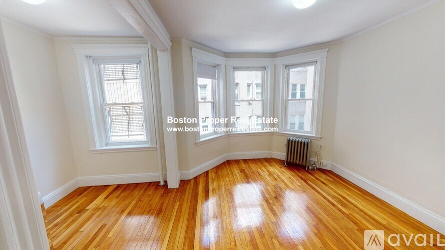 A room with wooden floors and white walls, with a window and a radiator.