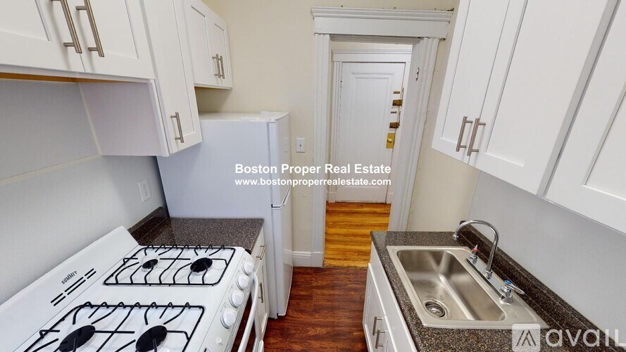A kitchen with white cabinets and a stove top oven.