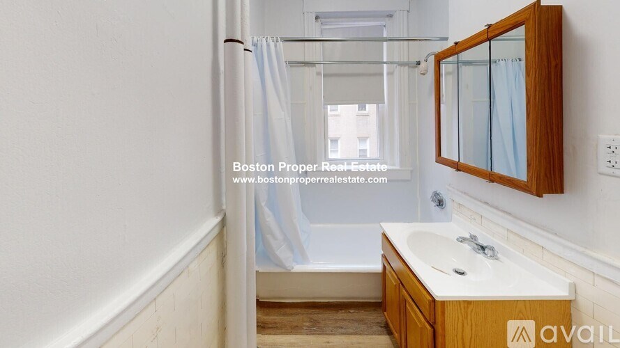 A bathroom with a wooden vanity and a shower with a blue curtain.