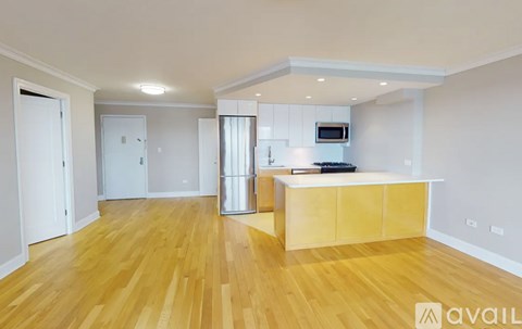 A spacious room with wooden flooring and a kitchen island with a microwave.