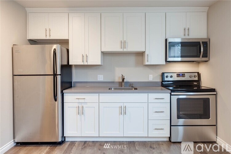 A kitchen with white cabinets and a stainless steel refrigerator.
