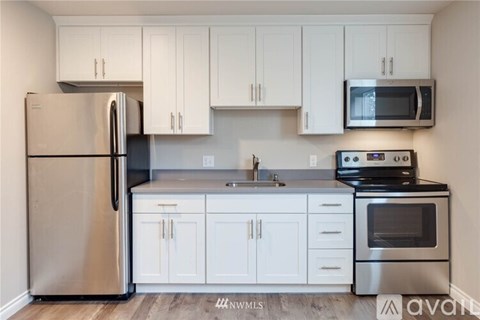 A kitchen with white cabinets and a stainless steel refrigerator.