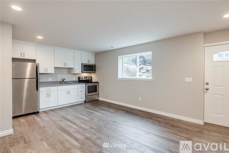 A kitchen with white cabinets and a stainless steel refrigerator.