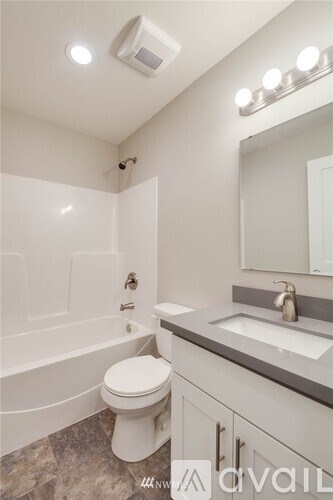 A bathroom with a toilet, sink, and mirror.