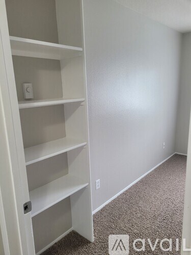 A white shelving unit in a room with a carpeted floor.