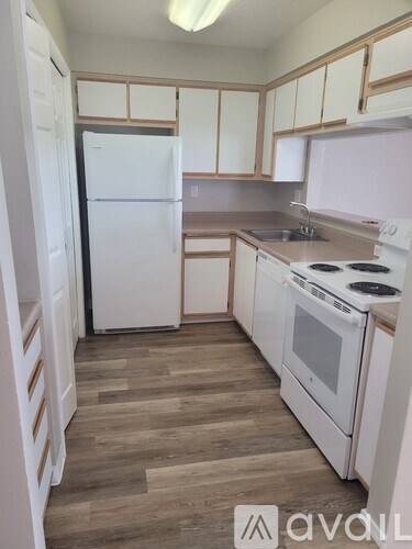 A kitchen with white appliances and wooden floors.