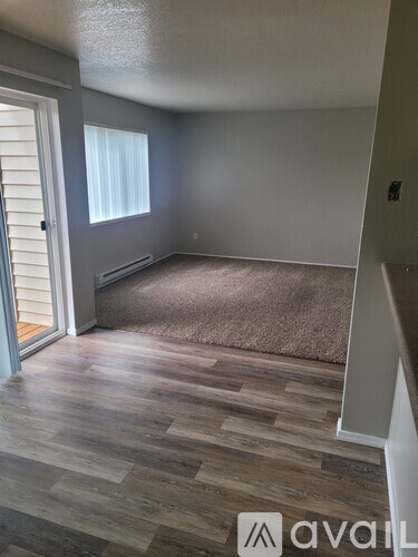 A room with wooden flooring and a window with blinds.