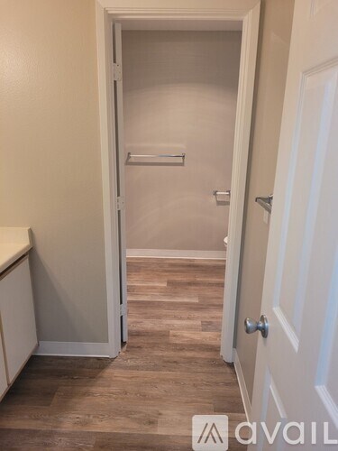A white door with a silver handle is in a room with wooden flooring.