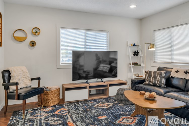 A living room with a black and white television, a leather couch, and a wooden coffee table.