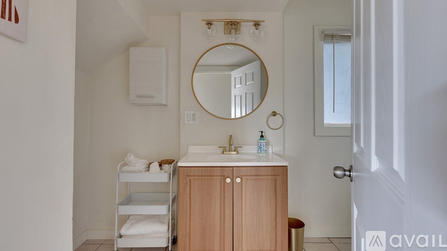 A bathroom with a round mirror and a wooden cabinet.