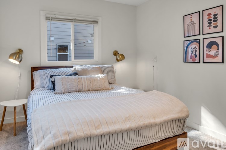 A bedroom with a bed, two lamps, and pictures on the wall.