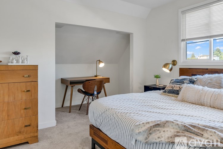 A bedroom with a bed, desk, chair, and lamp.