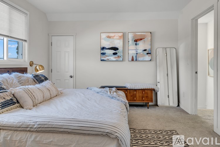 A bedroom with a large bed and two paintings on the wall.