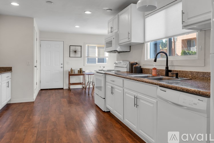 A kitchen with white cabinets and a brown floor.
