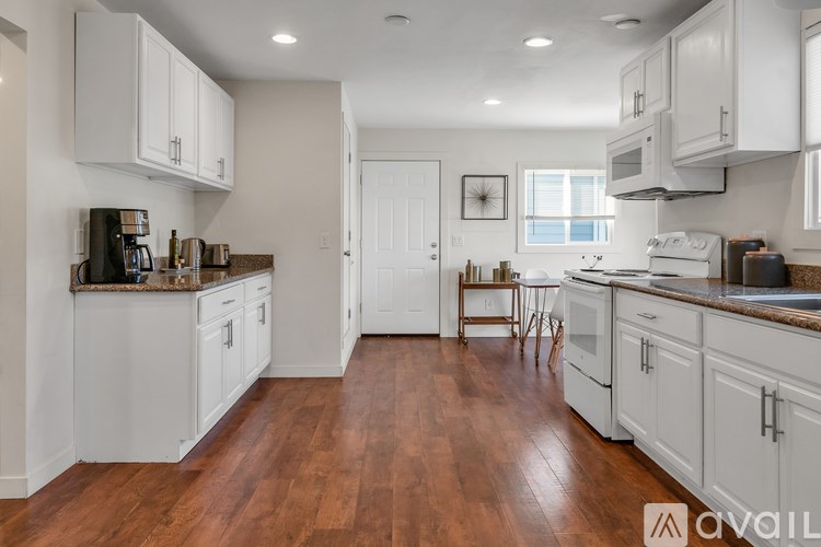 A kitchen with white cabinets and wooden floors.