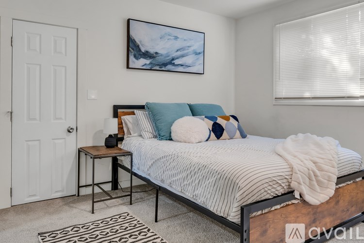 A bedroom with a bed, a nightstand, and a painting on the wall.