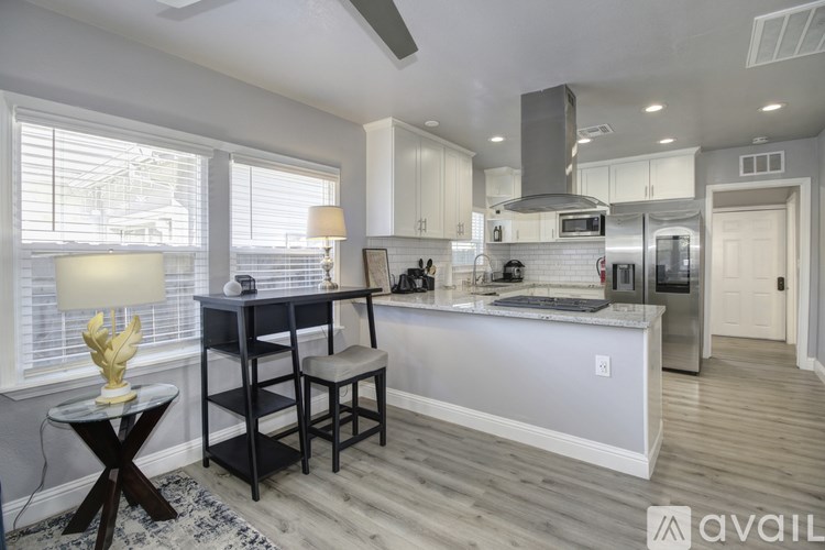 A modern kitchen with a desk and chair by the window.
