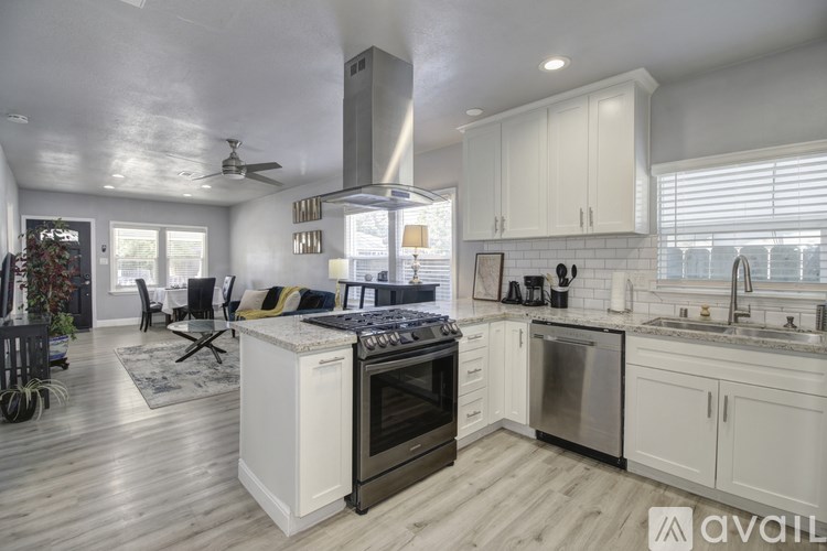 A modern kitchen with a black stove top oven and white cabinets.