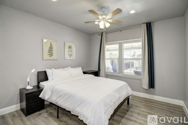 A bedroom with a white bed and a ceiling fan.