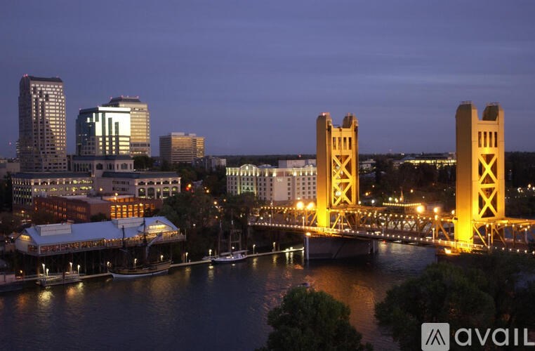 A cityscape at dusk with a bridge and buildings illuminated.