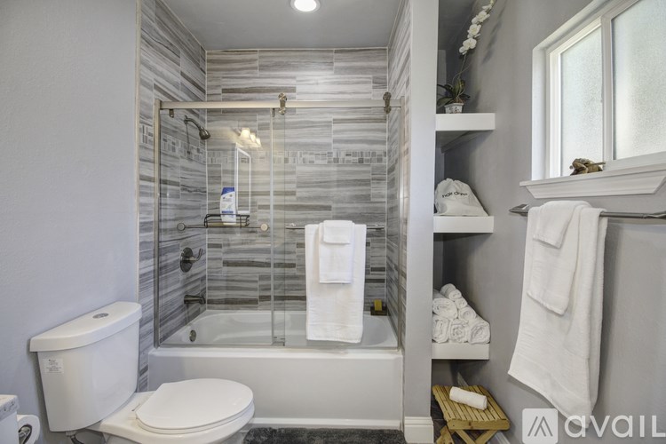 A bathroom with a toilet, a glass shower stall, and a towel rack.