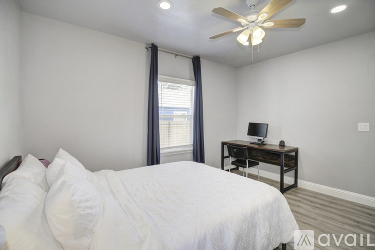 A bedroom with a bed, desk, and window.