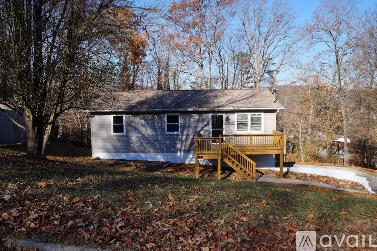 A house with a porch and a tree in front of it.